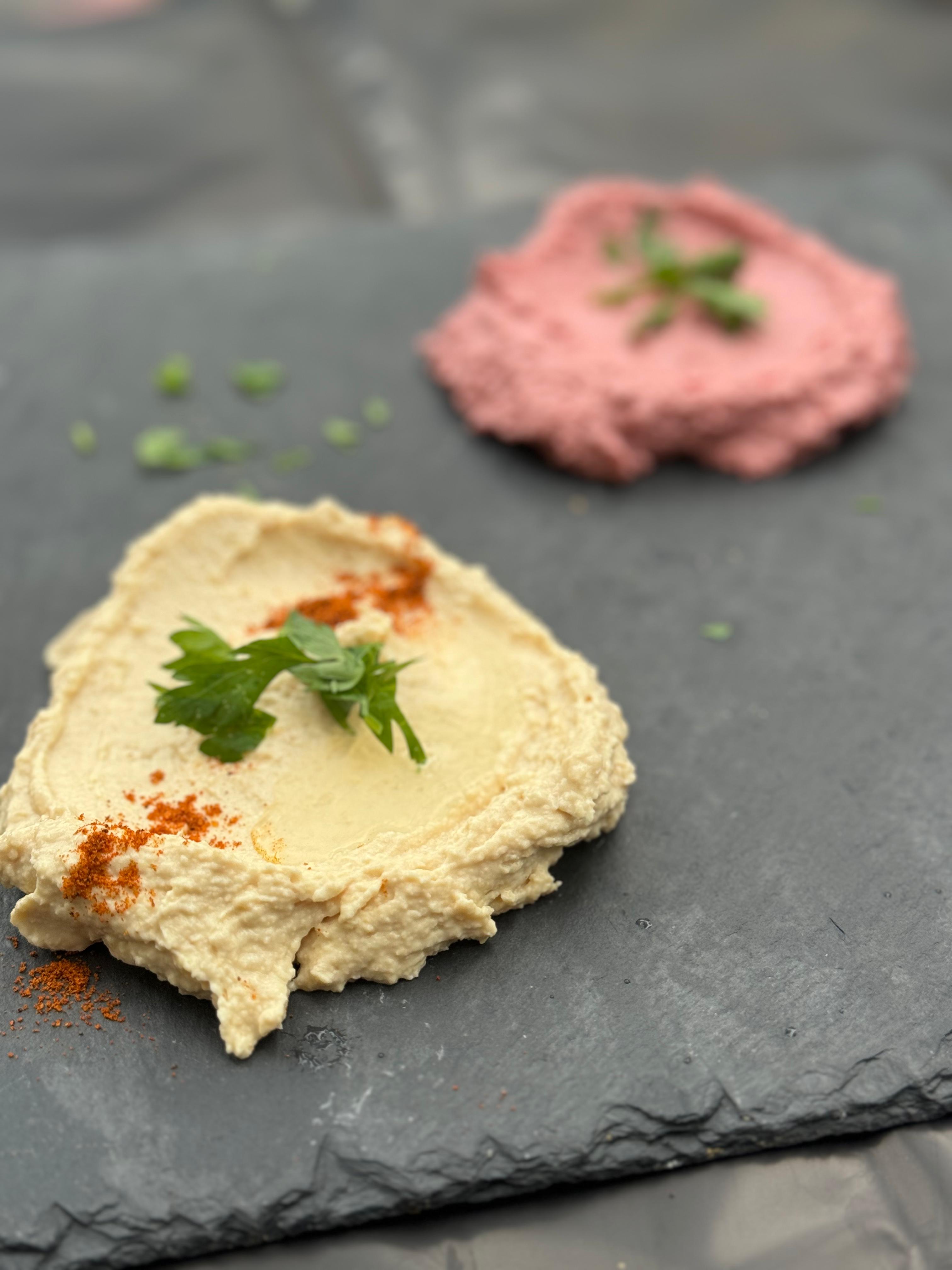 photo montrant du houmous, une entrée à base de pois chiches, en arrière plan, on voit le houmous de betterave.